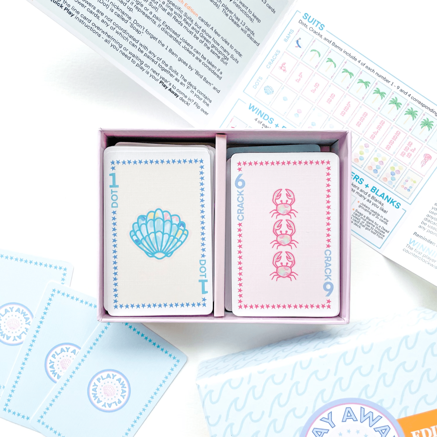 A box of Play Away Mahjong Beach Playing Card Deck opened to display the cards with beach-themed designs, including palm trees and crabs. Instructions are visible beside the box.