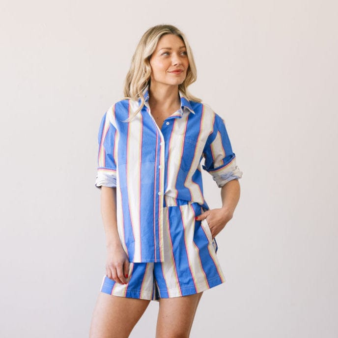 Woman wearing a blue and white striped outfit against a plain background