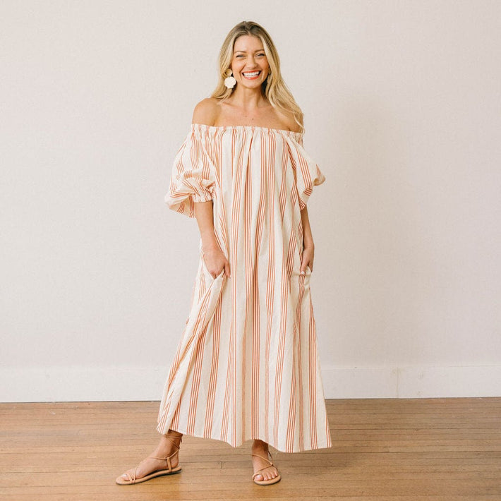 Woman wearing a striped off-shoulder dress against a plain background
