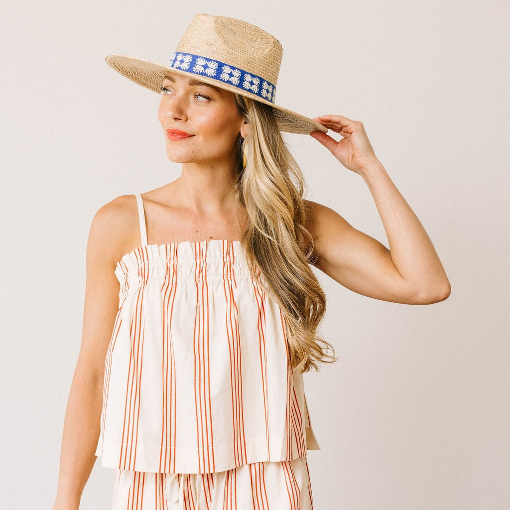 Woman wearing a straw hat with a decorative band against a plain background