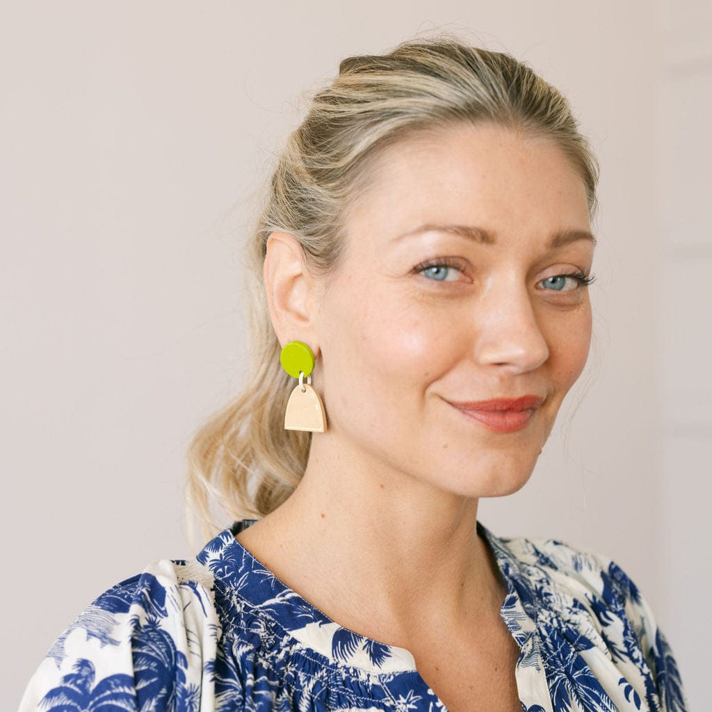 Woman wearing colorful earrings against a neutral background
