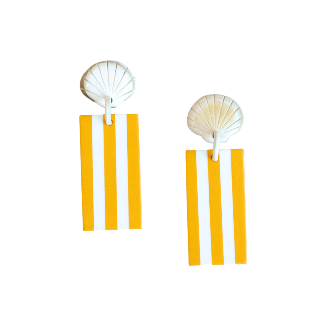 Pair of earrings with shell top and striped yellow and white bottom on a white background
