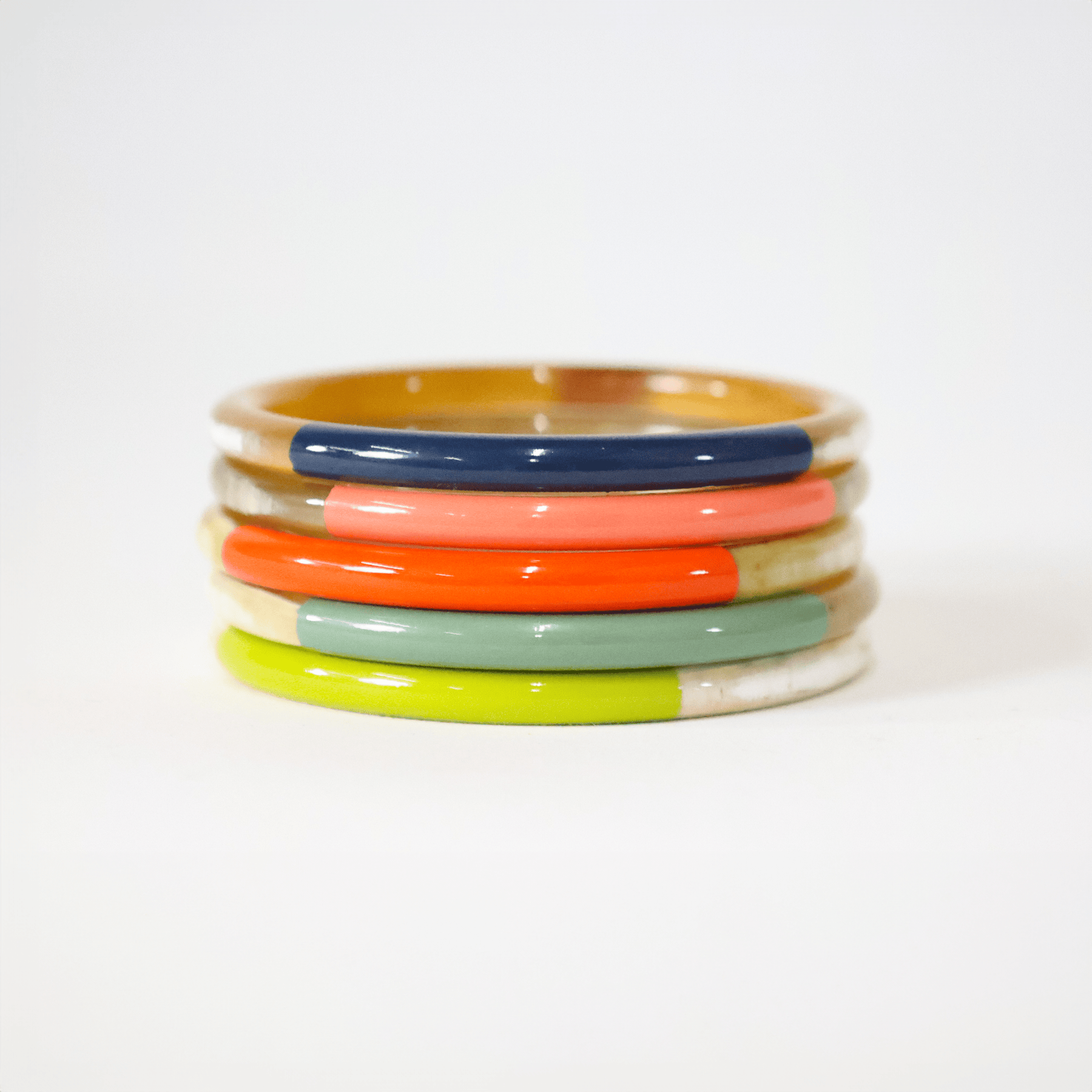 A set of colorful bangles in red, yellow, green, and blue, made from natural horn material.