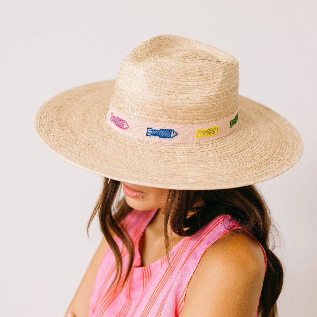 Person wearing a straw hat with visible brand logos on a plain background