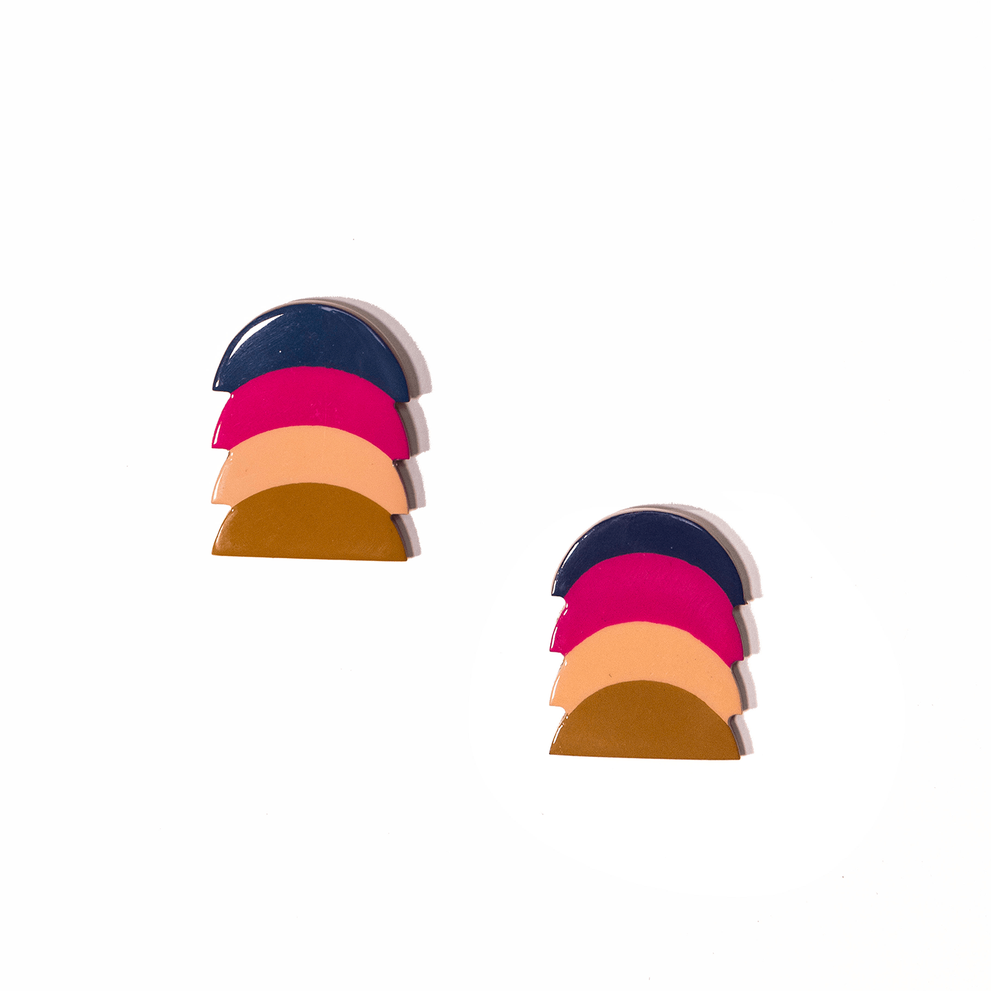 A pair of earrings featuring layered buffalo horn in navy, hot pink, blush, and terracotta colors, resembling a sunset.