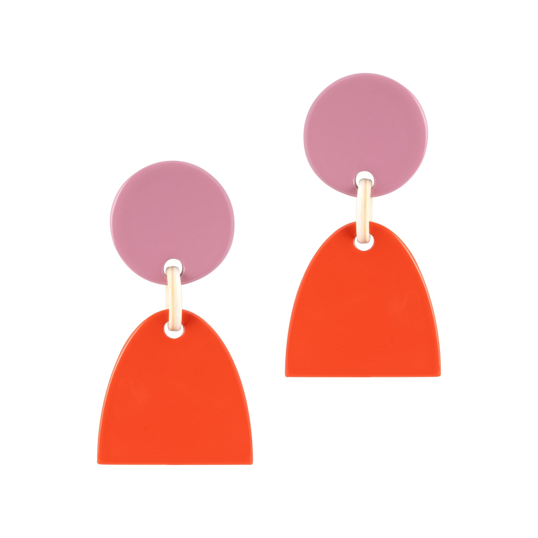 A pair of earrings featuring a soft pink circle connected to a bold red arch, dangling from a metallic post.