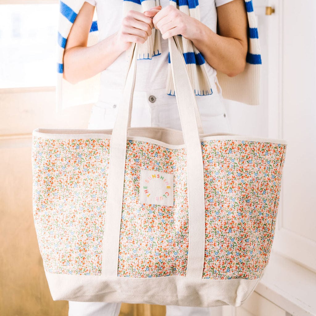 Person holding a floral-patterned tote bag with a neutral background