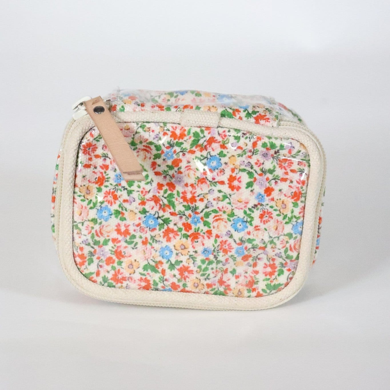 A floral jewelry case with a multicolored flower pattern and a beige zipper.