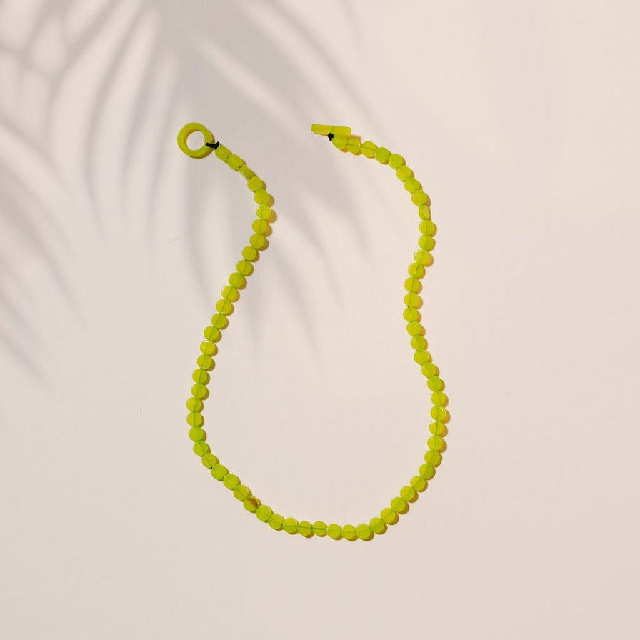 Neon green beaded necklace on a light beige background