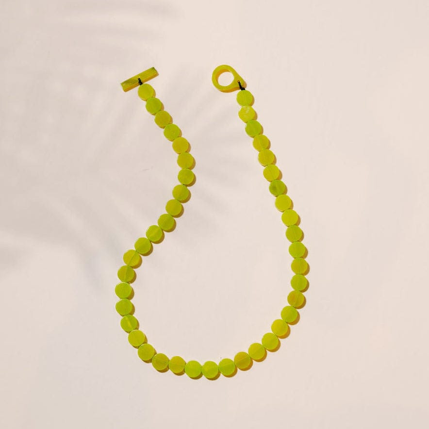 Neon green beaded necklace on a light beige background