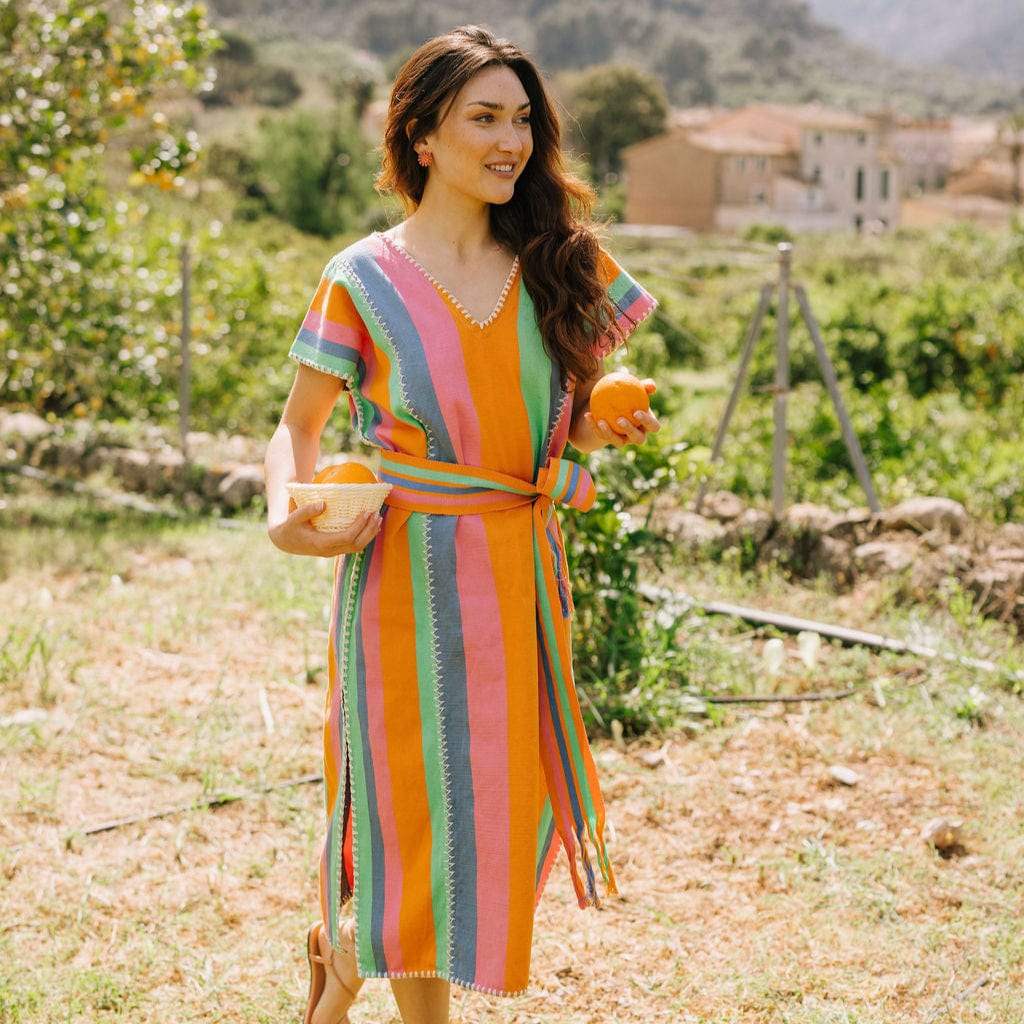 Woman in a colorful striped dress standing in a garden