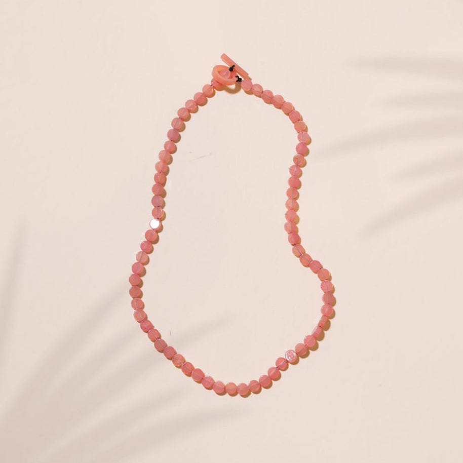 Pink beaded necklace on a beige background