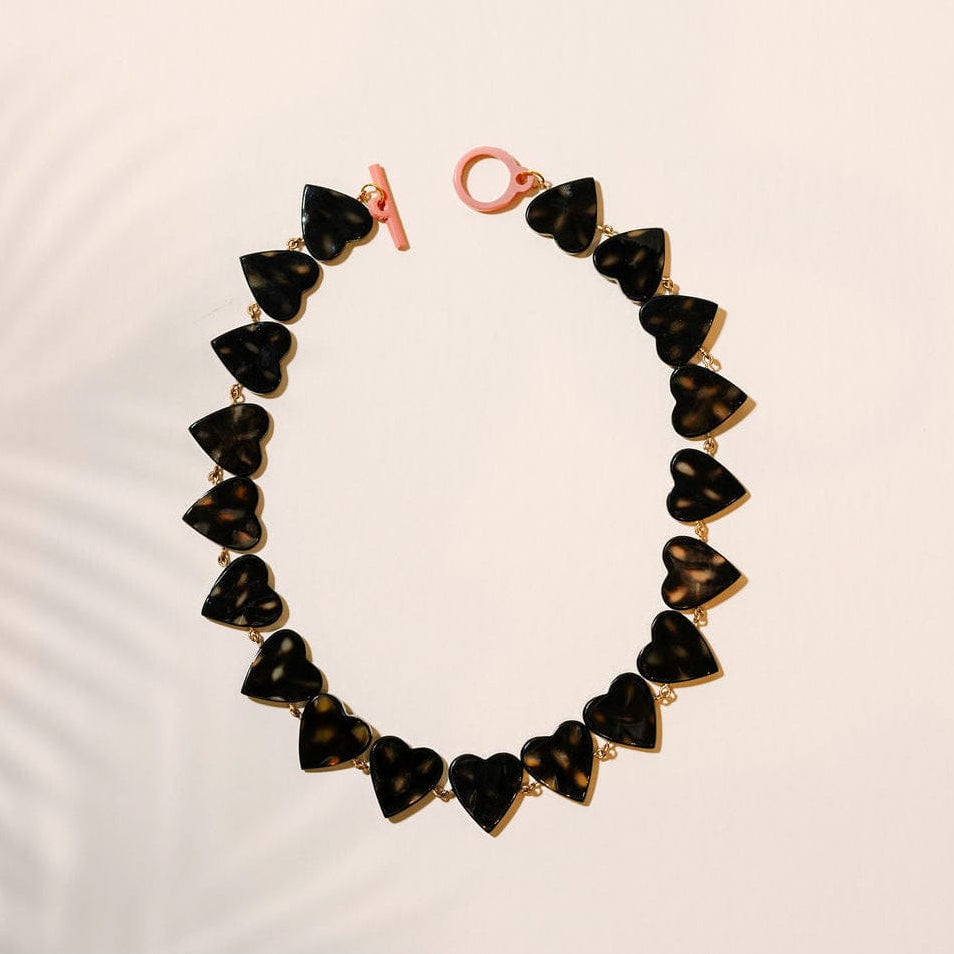 Bracelet with heart-shaped black and gold beads on a light pink background