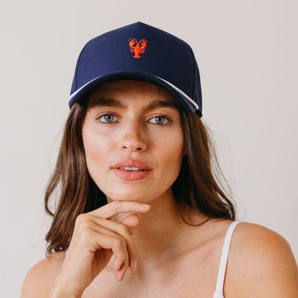 Woman wearing a navy blue cap with a red logo against a plain background
