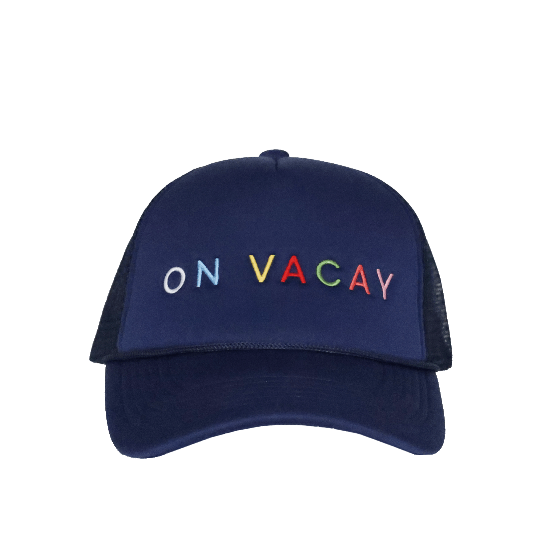 A navy blue trucker hat with 'ON VACAY' embroidered in multicolor letters on the front panel.
