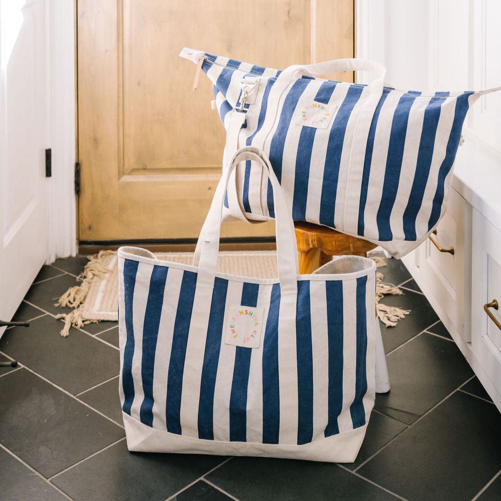 Blue and white striped tote bag and pillow on a tiled floor.