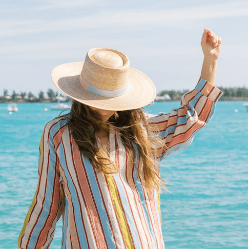 Woman in a striped dress and sun hat by a body of water