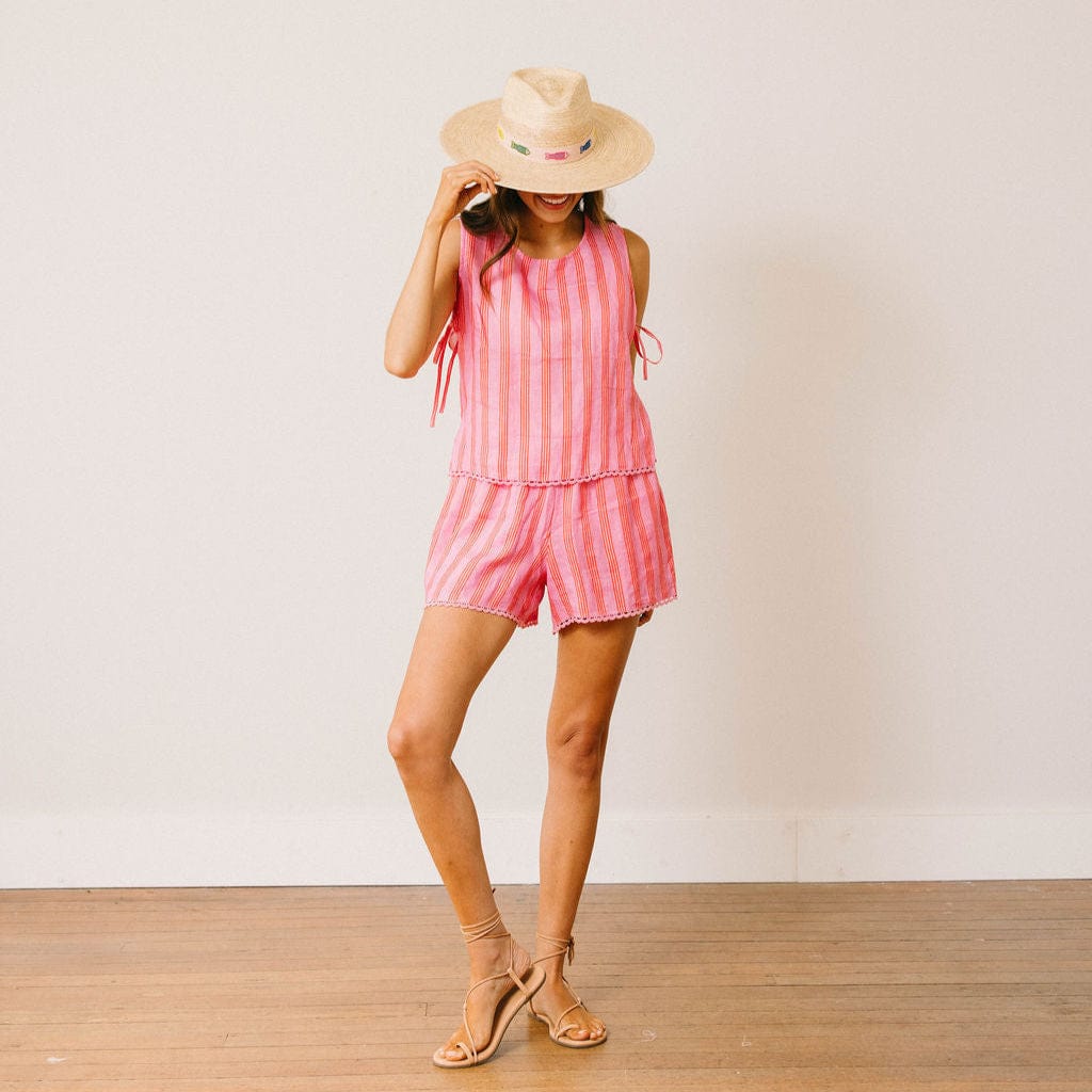 Woman wearing a pink striped outfit and straw hat against a white background