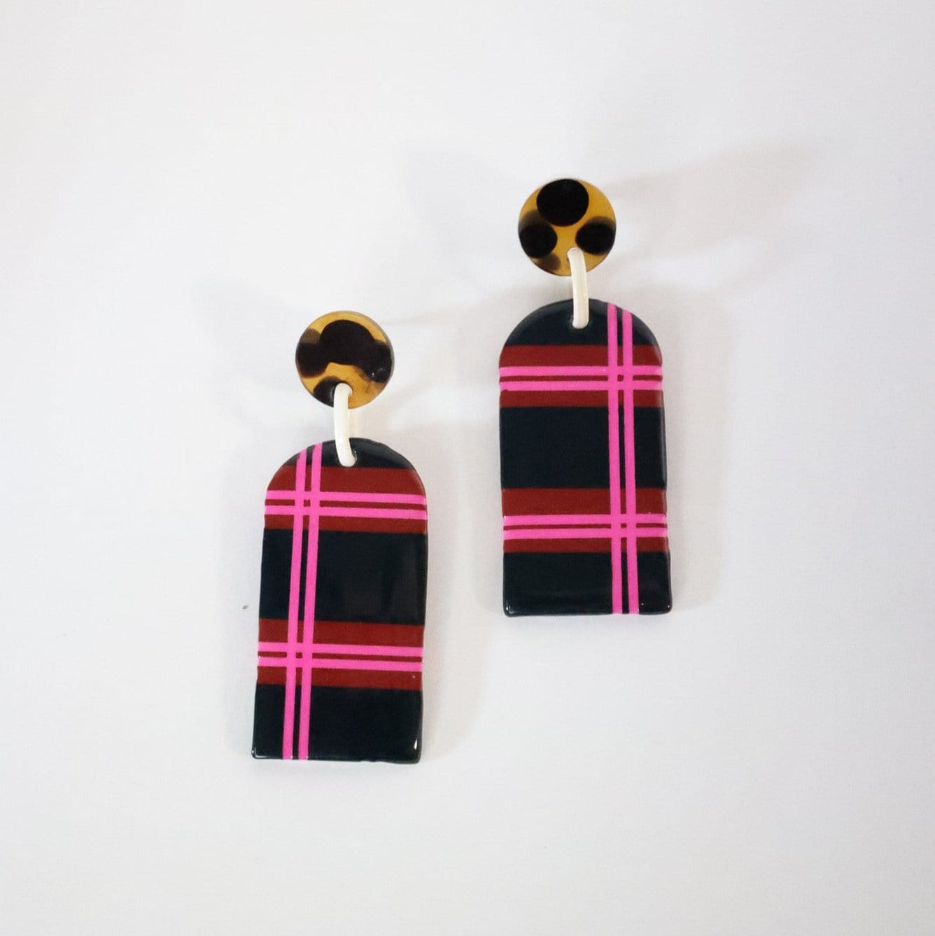 A pair of earrings featuring a plaid pattern with dark blue and pink colors, and a buffalo horn attachment.