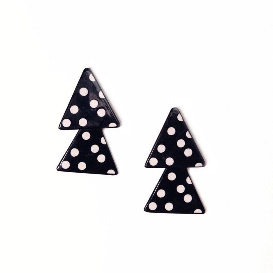 A pair of navy blue and white polka dot triangle-shaped earrings on a white background.