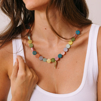 Woman wearing a colorful beaded necklace with a plain background