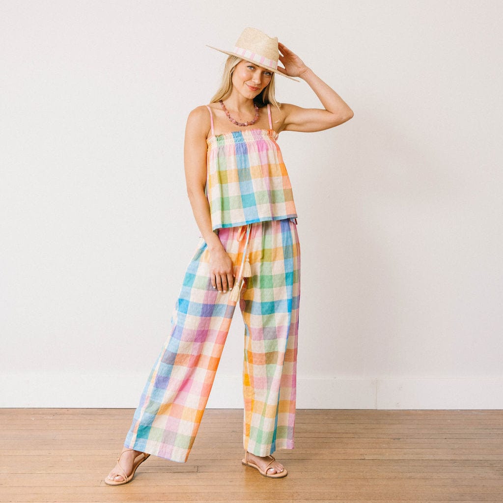 Woman wearing a colorful plaid outfit with a hat against a white background