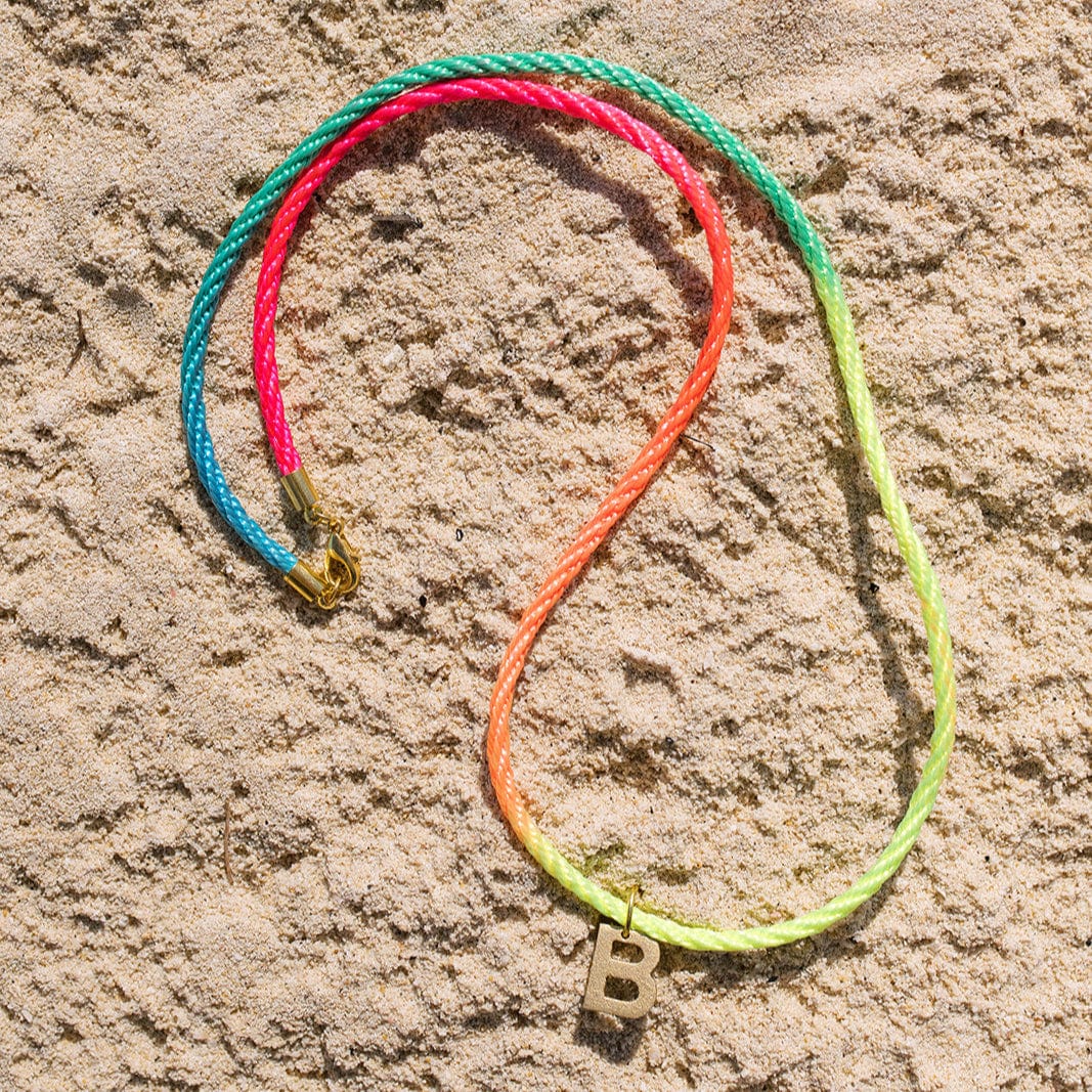 Colorful bracelet with a letter 'B' charm on sand