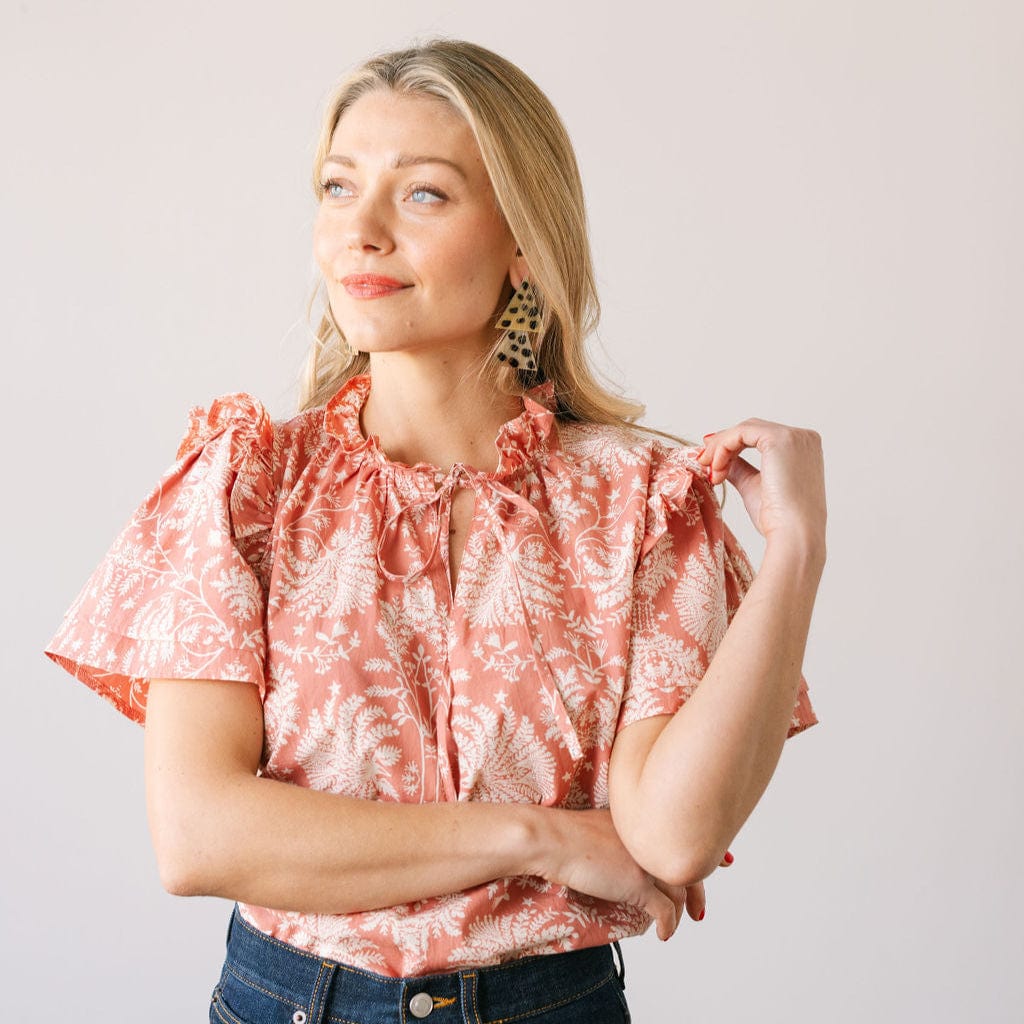 Woman wearing a pink floral blouse against a plain background