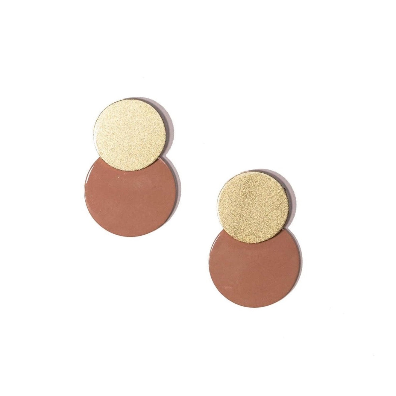 A pair of metallic gold and light pink circle earrings on a white background.