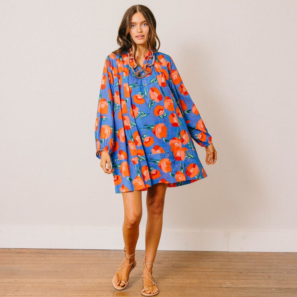 Woman wearing a colorful floral dress against a plain background