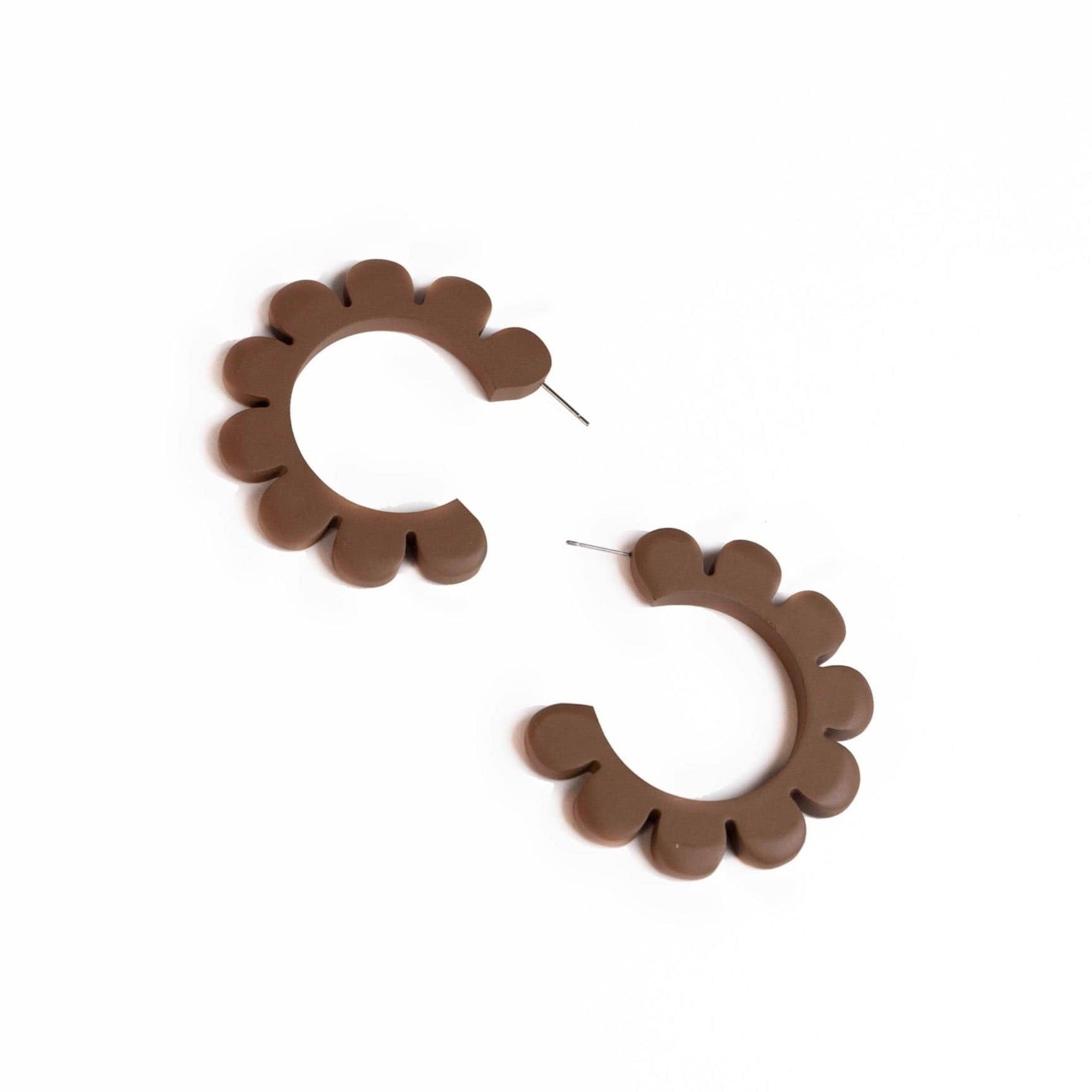 A pair of matte brown flower outline hoop earrings on a white background.