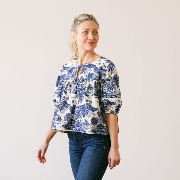 Woman wearing a blue and white floral blouse with a plain background