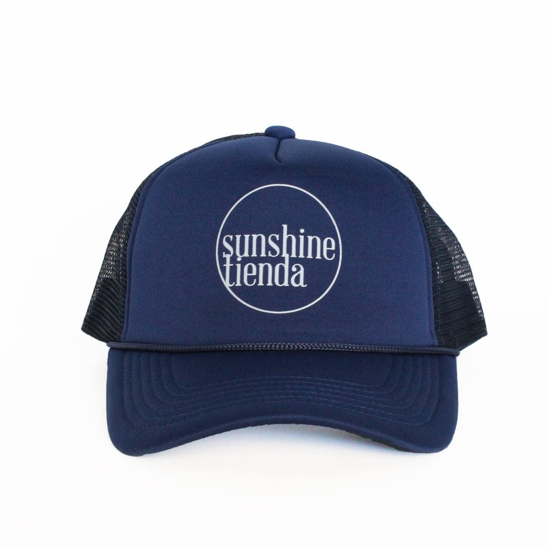 A navy and white trucker hat with 'sunshine tienda' embroidered on the front.