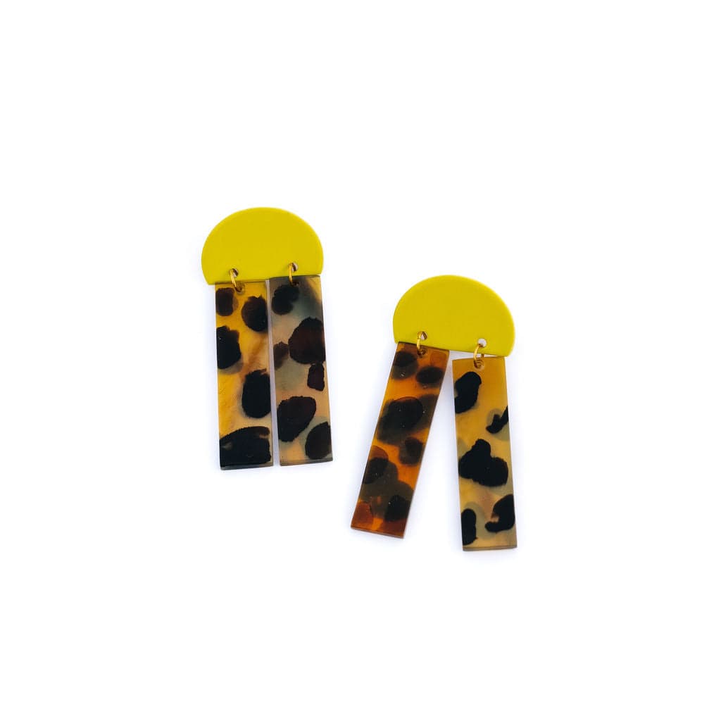 A pair of dangle earrings with a yellow top and a pattern resembling painted tortoise shell, attached to stainless steel ear posts.